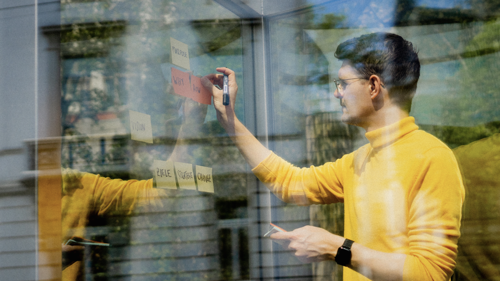 Porträt von Konrad Weber mit Post-its zu Purpose, Why, How und What.